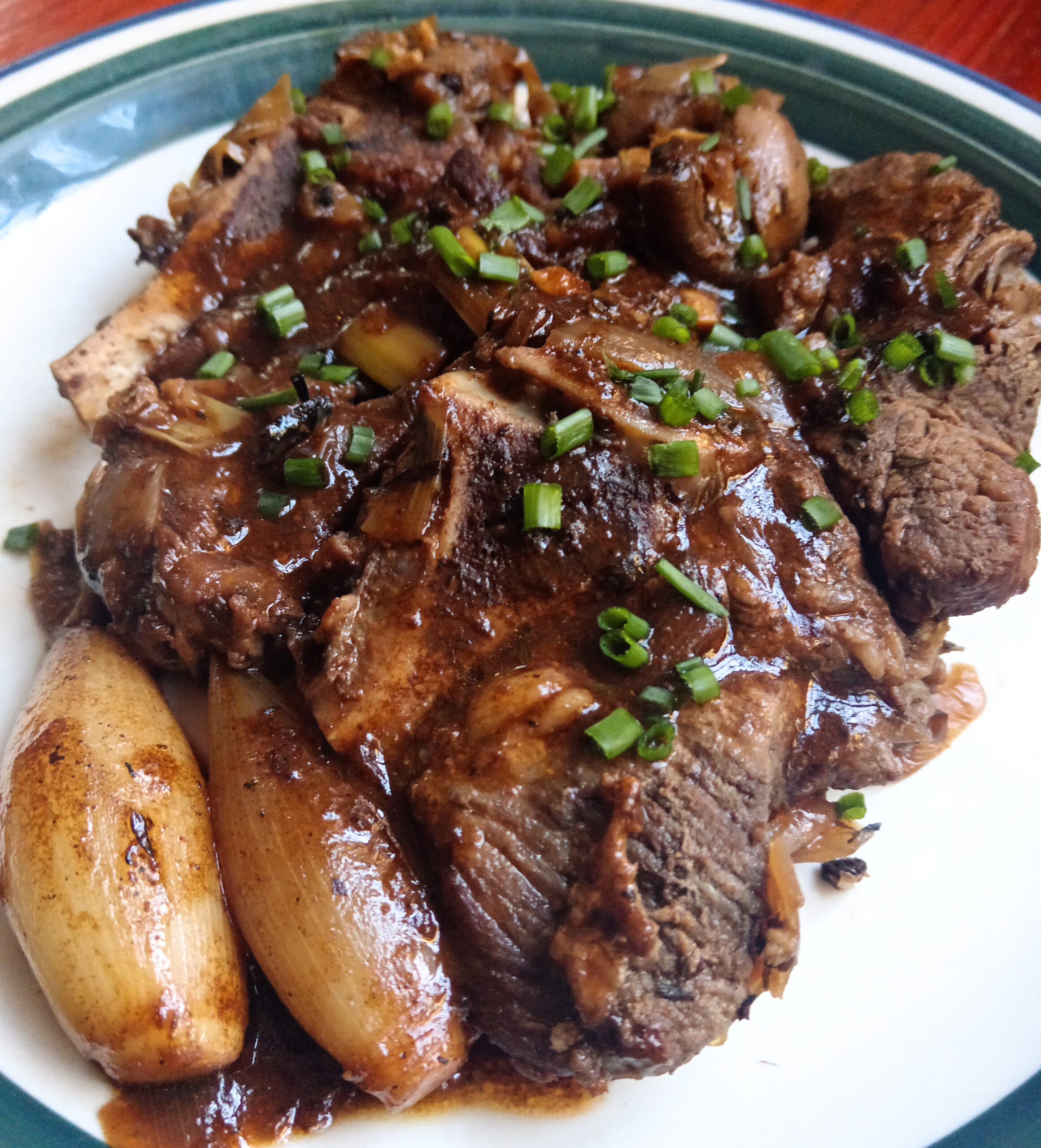 Slow-braised chuck beef with whole shallots, mushrooms and a rich dark onion jus, garnished with fresh chives.