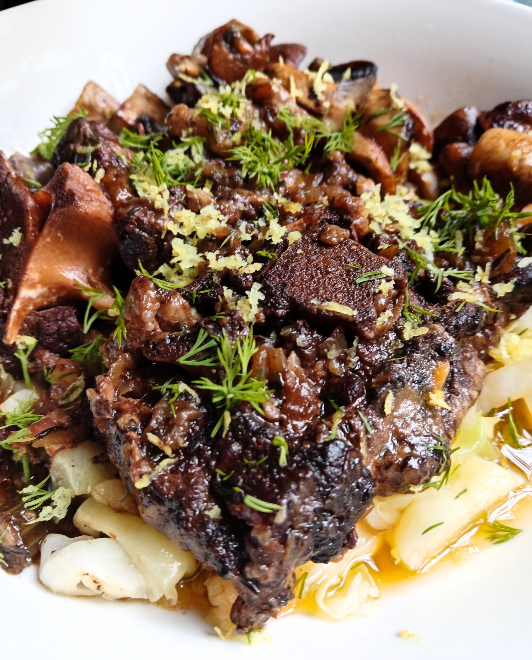 Slow-cooked oxtail served on braised cabbage with sautéed mushrooms, fresh dill, and lemon zest.