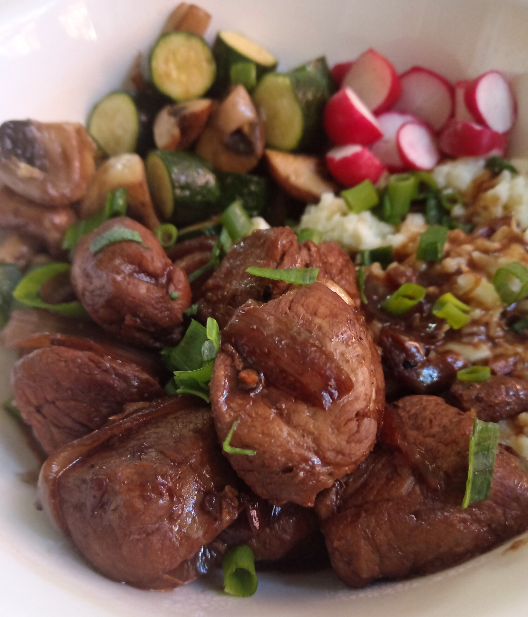 Keto pork tenderloin adobo served with cauliflower mash, sautéed zucchini and mushrooms, spring onion, and sliced radishes.